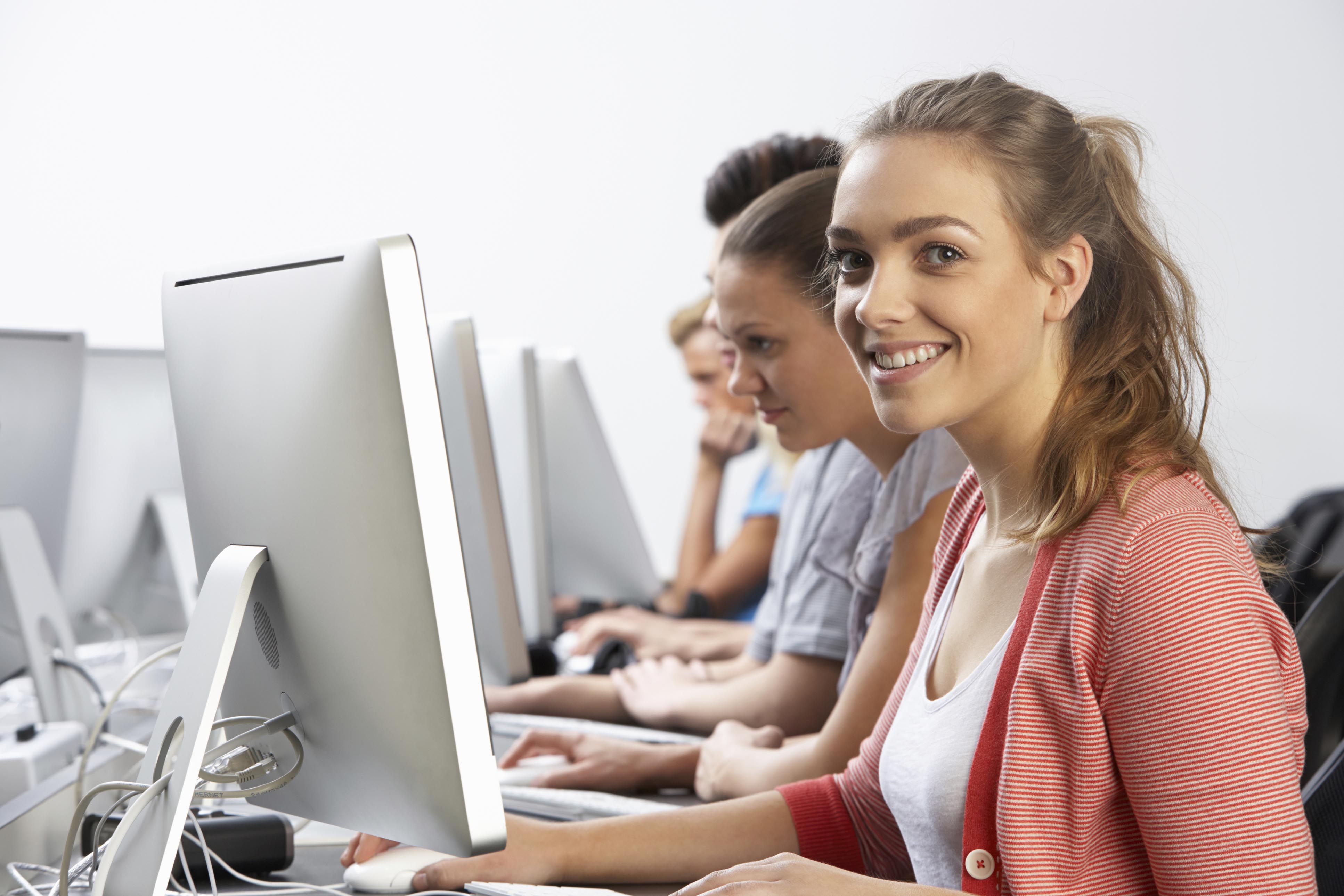 Girl smiling and classmates in background in a computer class.
